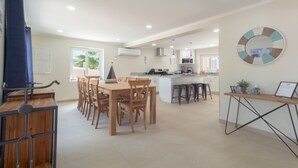 Une cuisine moderne dotée d’un îlot central, de meubles blancs et d’un coin repas avec des chaises en bois.