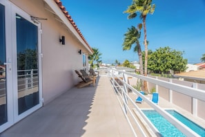 Un balcon avec piscine, un espace salon extérieur et une vue sur la mer.