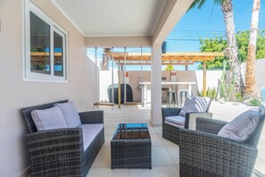An outdoor patio area with wicker furniture, a swing set, and a barbecue grill.
