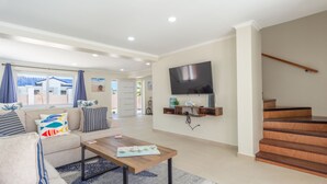 Un salon moderne avec un canapé, une table basse et un téléviseur à écran plat fixé au mur.