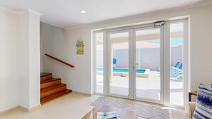 Un intérieur moderne avec un escalier en bois, une porte vitrée donnant sur un espace piscine et une petite table avec des magazines.