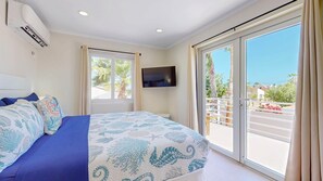 Une chambre à coucher avec un lit, une télévision, une fenêtre et un balcon.