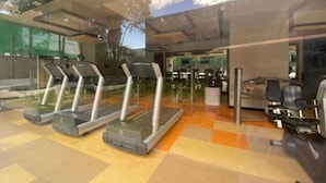 A gym with treadmills, exercise bikes, and a weight bench area.