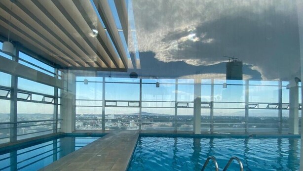 An indoor swimming pool with a view of a cityscape through large windows.