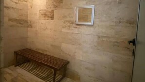 A small, dimly lit room with a wooden bench and a framed picture on the wall.