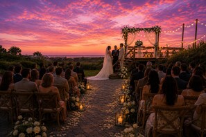 Une cérémonie de mariage où les invités sont assis sur des chaises disposées en rangées, face à un couple se tenant sous une arche fleurie.