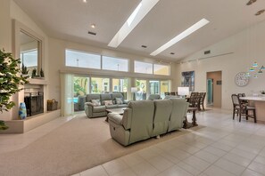 Ein geräumiges Wohnzimmer mit einer großen Couch, einem Essbereich und einem Kamin.