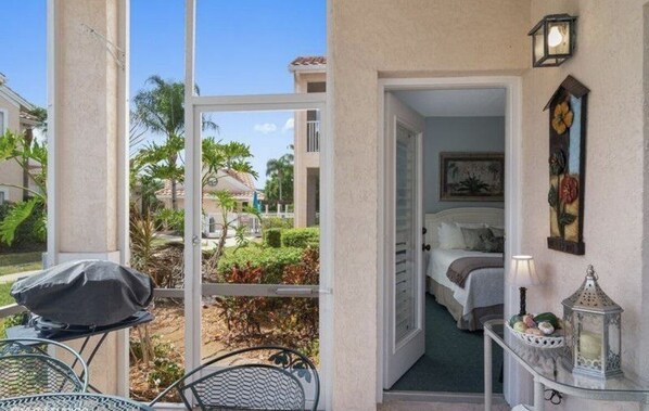A hotel room with a balcony, a bed, a nightstand, and a view of the surrounding area. - PGA Apartment Clean, Relaxing - GOLF/METS (Port St. Lucie)