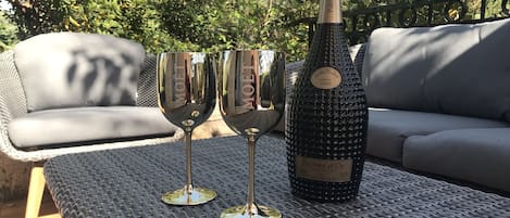 A bottle of wine and two glasses on a metal table outdoors.