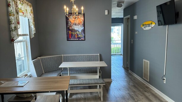 Uma sala de jantar moderna com mesa e bancos de madeira, um lustre e um pôster grande na parede.