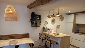 Eine moderne Küche mit einer Holztheke, weißen Schränken und Pendelleuchten.