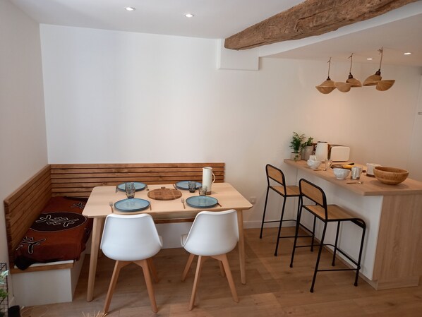 A dining area with a wooden table set for two, white chairs, and a bench. - MISS PRUNE'S APARTMENT IN THE HEART OF VANNES (Vannes)