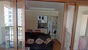 Ein Wohnzimmer mit einer Couch, einem Esstisch und einer Küche im Hintergrund.