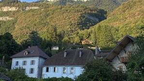 Paisagem montanhosa com um pico rochoso imponente e uma aldeia com casas tradicionais.