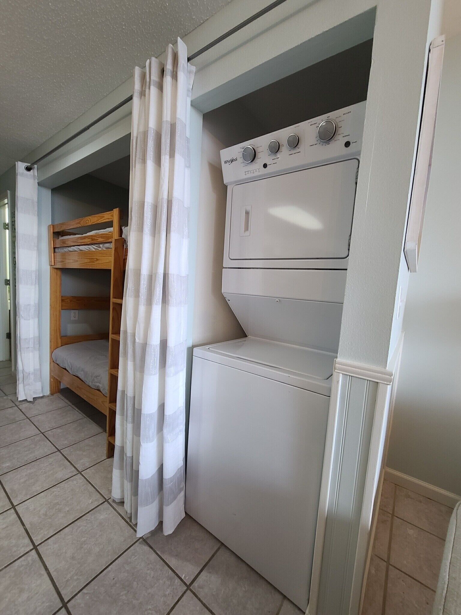 Una habitación pequeña con literas, lavadora y secadora.