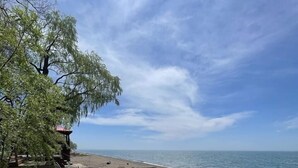 A beach with a wooden deck, a few benches, and a small structure. - Rustic Beachfront Tiny Cabin Retreat Near Point Pelee (Leamington)