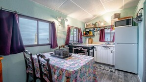 A compact kitchen with a dining table, chairs, a refrigerator, and a microwave. - Rustic Beachfront Tiny Cabin Retreat Near Point Pelee (Leamington)