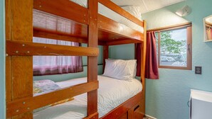 A bunk bed room with a window, a bedside table, and a wall-mounted light fixture. - Rustic Beachfront Tiny Cabin Retreat Near Point Pelee (Leamington)