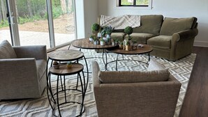 Una sala de estar con un sofá, dos sillones, una mesa de centro y una alfombra.