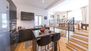 Una cucina moderna con mobili scuri, forno integrato e zona pranzo con tavolo e sedie in legno.