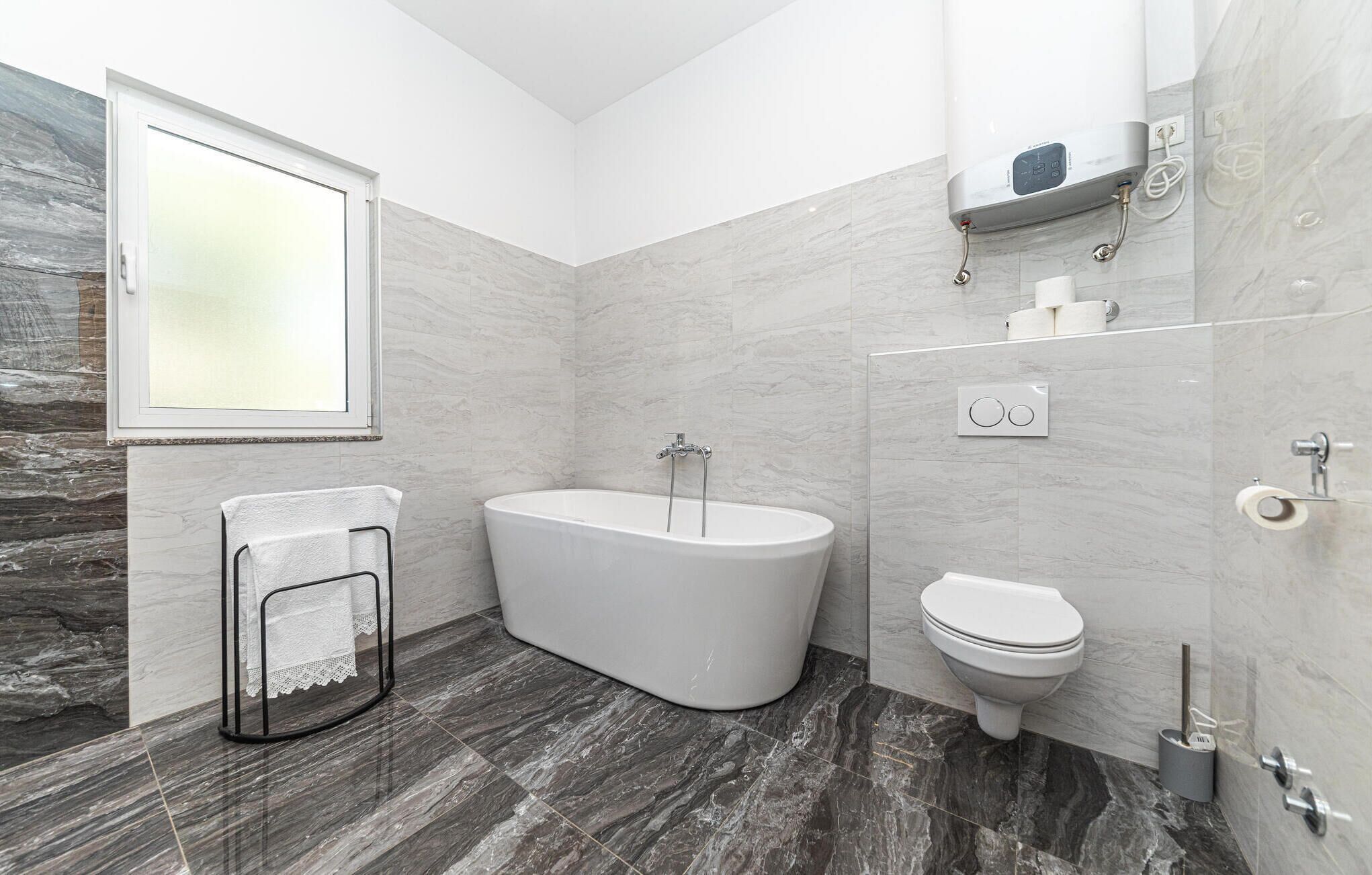 A modern bathroom with a freestanding bathtub, a toilet, and a shower.