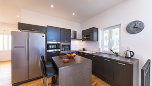 Una cucina moderna con isola centrale, elettrodomestici in acciaio inossidabile e una sveglia appesa al muro.