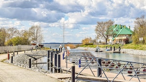 A riverside dock with boats, a green-roofed building, and a stone wall.