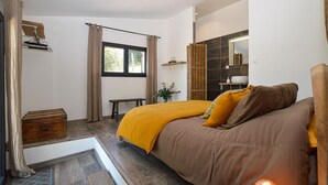 Une chambre à coucher avec un lit, un banc, une fenêtre, un miroir et une table de chevet.