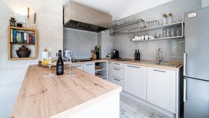 A modern kitchen with white cabinets, a wooden countertop, and a built-in wine rack.