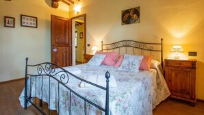 A bedroom with a four-poster bed, wooden headboard, floral bedding, and a nightstand with a lamp. - Lovely home in Buggiano with kitchen (Buggiano)
