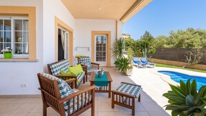 A covered patio with wooden furniture, a pool, and a view of the backyard. - Awesome home in Cala Bona (Cala Bona)