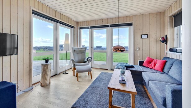 A spacious living room with a large window, a grey sofa, a wooden coffee table, and a TV mounted on the wall. - Stunning home in Faaborg with WiFi (Faaborg)