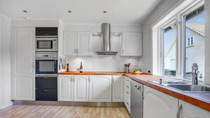 Una cocina moderna con armarios blancos, electrodomésticos de acero inoxidable y encimera de madera.