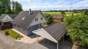 Una casa moderna con techo inclinado, un porche cubierto y un césped bien cuidado.