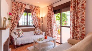 A cozy living room with a sofa, a glass coffee table, and a window with floral curtains. - Gorgeous home in Torrox with WiFi (Torrox)