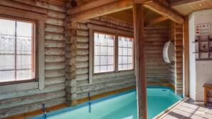 Een vakantiehuisje van hout met een zwembad, houten wanden en grote ramen.