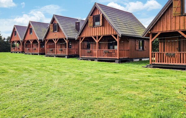 Une rangée de cabanes en bois aux toits en pente, chacune dotée d’un porche et d’une petite fenêtre.