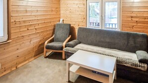 Ein Holzblockbau-Innenraum mit einer Couch, einem Sessel und einem kleinen Tisch.