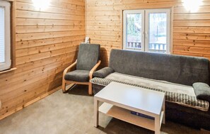 L'intérieur d'un chalet en bois, avec un canapé, un fauteuil et une petite table.