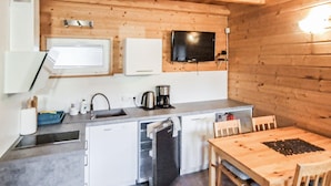 Eine kleine Küche mit Spüle, Kaffeemaschine und Mikrowelle. Ein Holztisch mit Stühlen steht bereit.