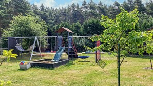 Ein Spielplatz mit Schaukeln, Rutschen und einer Kletterkonstruktion.