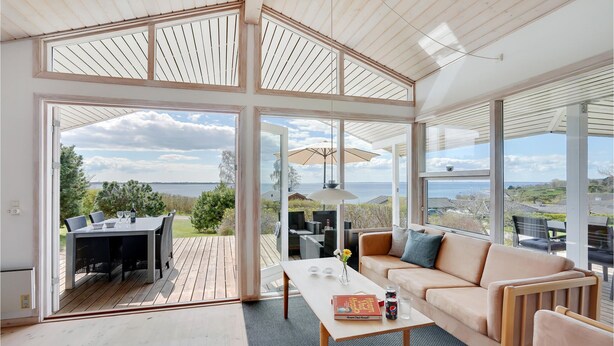 Amplia habitación con grandes ventanales que ofrecen vista al mar y un área de terraza con mobiliario exterior.