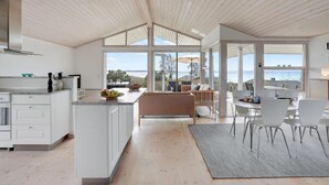 Una cocina moderna con una isla grande, un comedor con vistas y un rincón de estar acogedor.