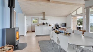 Una cocina moderna con armarios blancos, una isla central y un estufa a leña.