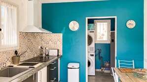 Een moderne keuken met een muur in blauwgroen, een koffiezetapparaat, een broodrooster en een prullenbak.