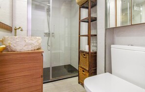 Ein Badezimmer mit einem Holzlagerflächezimmermeier, einer Duschkabine aus Glas und einer weißen Toilette.
