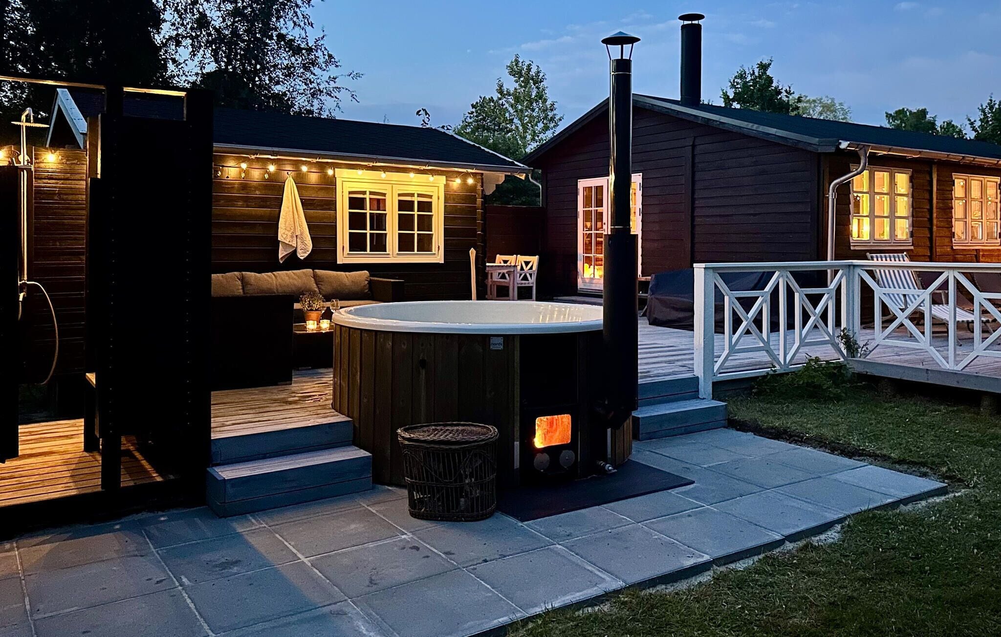 A wooden cabin with a hot tub, outdoor seating, and a fireplace.