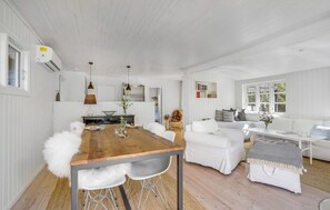 Cozy seating area surrounds a central dining table with a bookshelf in the background.
