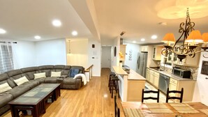 A modern living room with a sectional sofa, a wooden coffee table, and a dining area with a wooden table and chairs. - Creek house with expansive mountain views (ashland)