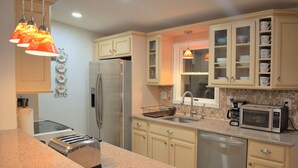 A kitchen with granite countertops, a stainless steel refrigerator, a built-in dishwasher, and a microwave. - Creek house with expansive mountain views (ashland)